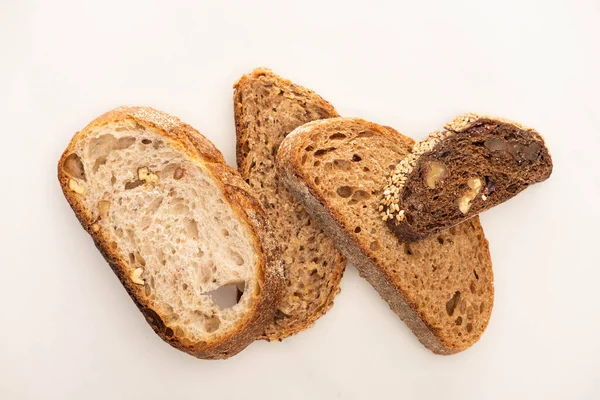 Vista superior de rebanadas frescas de pan de grano entero sobre fondo blanco - foto de stock