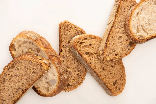 Vista superior de rebanadas frescas de pan de grano entero sobre fondo blanco - foto de stock