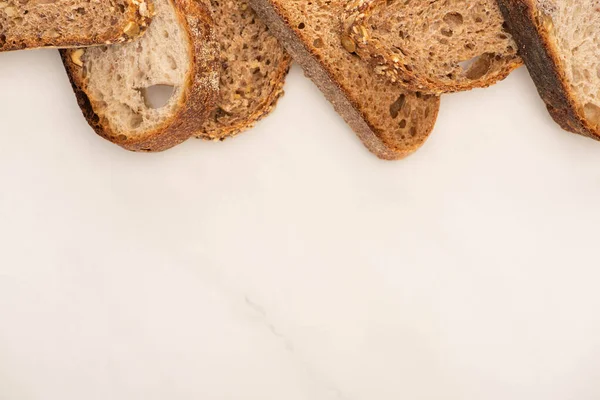 Vista superior de rebanadas frescas de pan de grano entero sobre fondo blanco con espacio para copiar - foto de stock