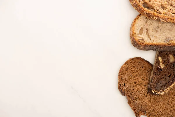 Vista superior de rebanadas frescas de pan de grano entero sobre fondo blanco con espacio para copiar - foto de stock