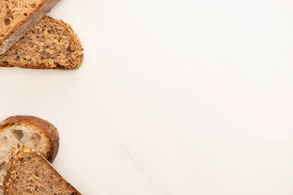 Vista superior de rebanadas frescas de pan de grano entero sobre fondo blanco con espacio para copiar - foto de stock