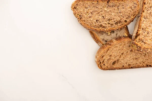 Вид сверху на свежий цельнозерновой хлеб ломтики на белом фоне с копировальным пространством — стоковое фото