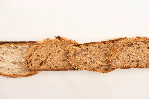 Vista superior de rebanadas de pan de grano entero en línea sobre fondo blanco - foto de stock