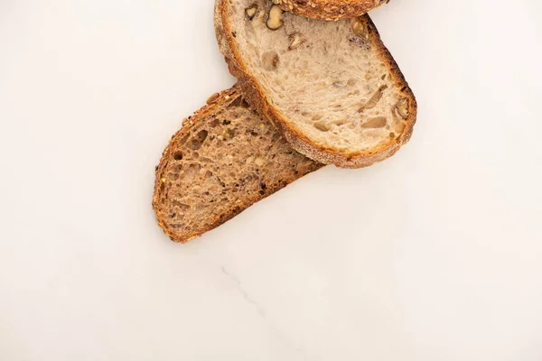 Vista superior de saborosas fatias de pão de grão inteiro no fundo branco com espaço de cópia — Fotografia de Stock
