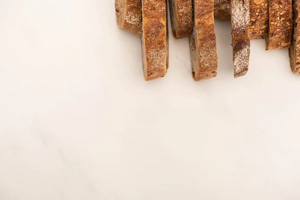 Vista dall'alto di gustose fette di pane integrale su sfondo bianco con spazio copia — Foto stock