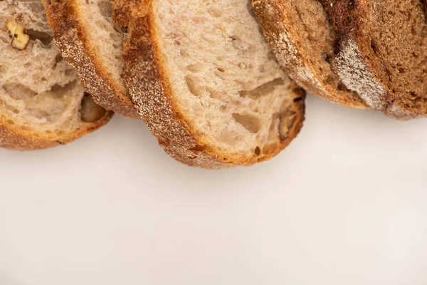 Vue de dessus des tranches de pain de blé entier frais sur fond blanc — Photo de stock