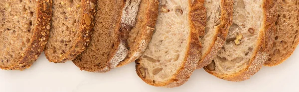 Vista dall'alto di fette di pane integrale fresco su sfondo bianco, colpo panoramico — Foto stock