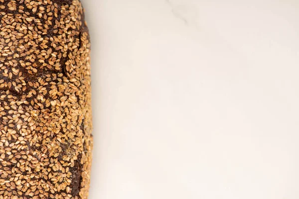 Top view of fresh whole wheat bread loaf with sesame on white background with copy space — Stock Photo