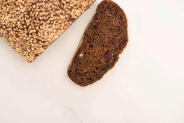 Вид зверху на свіжий коричневий хліб скибочки і хліб на білому тлі — стокове фото