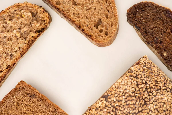 Vue du dessus des tranches de pain de blé entier frais et du pain sur fond blanc — Photo de stock