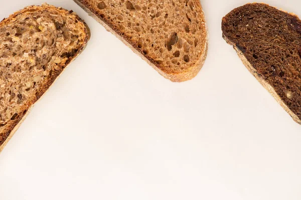 Vista dall'alto di fresche fette di pane integrale su sfondo bianco con spazio copia — Foto stock