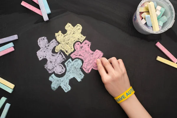 Vista superior da mulher em pulseira desenho quebra-cabeça com giz rof Dia Mundial da Consciência do Autismo — Fotografia de Stock