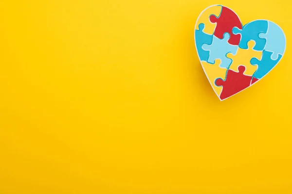 Vista superior del corazón colorido con rompecabezas en amarillo para el Día Mundial de la Concientización del Autismo - foto de stock