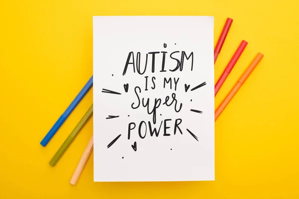 Vue de dessus des stylos en feutre sur feuille de papier avec autisme est mon inscription super puissance sur jaune — Photo de stock