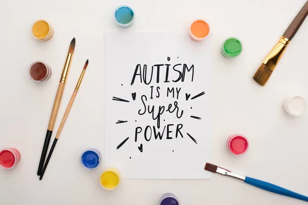 Vista superior de tintas, pincéis e cartão com autismo é o meu super poder lettering em branco — Fotografia de Stock