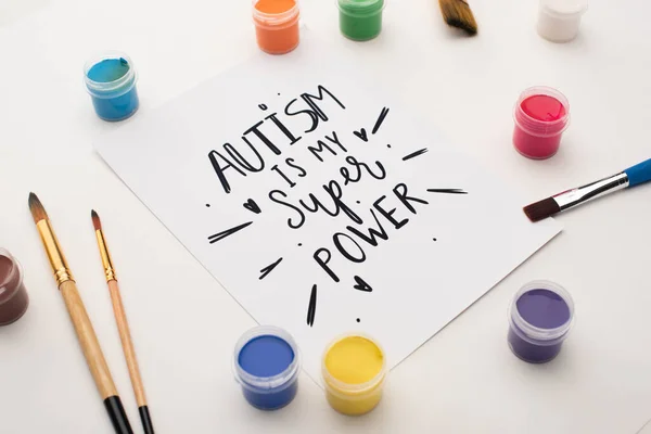 Pinturas, pinceles y tarjetas con autismo es mi súper poder de letras en blanco - foto de stock