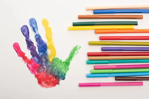 Vista dall'alto della colorata impronta a mano e marcatori sul bianco per la Giornata Mondiale della Consapevolezza dell'Autismo — Foto stock