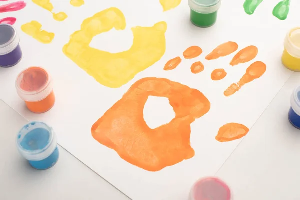 Primer plano de coloridas huellas de manos y pinturas en blanco para el Día Mundial de la Concientización sobre el Autismo - foto de stock