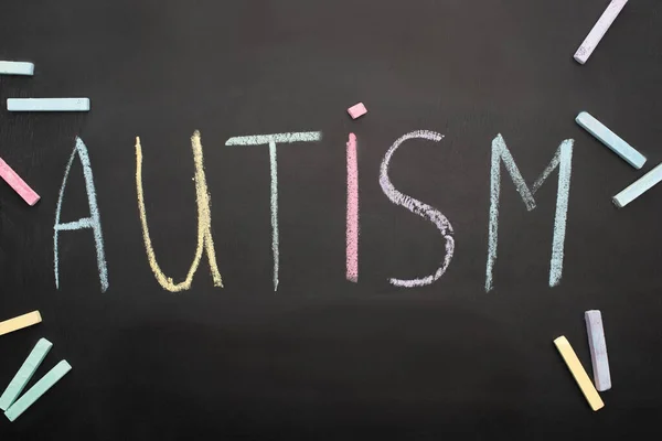Vista superior de la palabra autismo en pizarra con tiza de colores - foto de stock