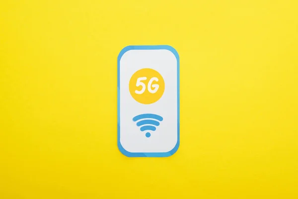 Вид сверху на 5g буквы на бумажном смартфоне на желтом фоне — стоковое фото