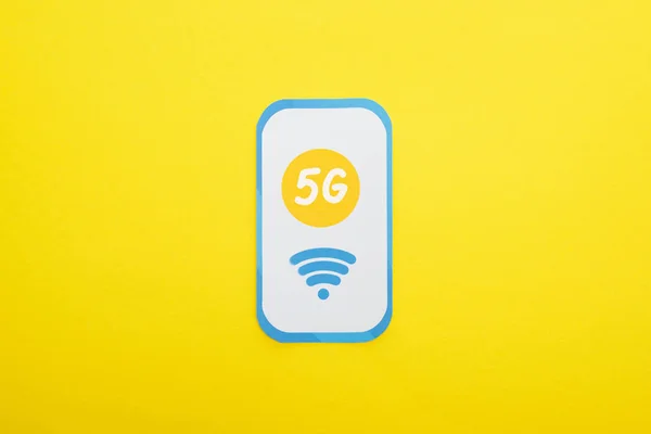 Top view of 5g lettering on paper smartphone on yellow background — Stock Photo