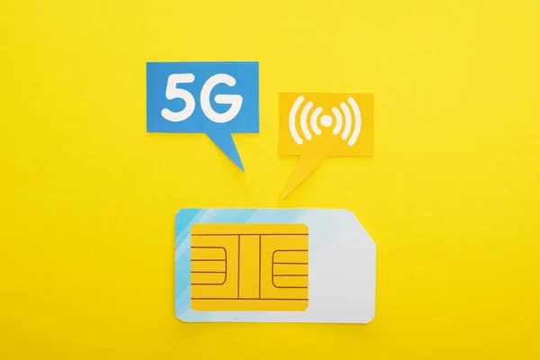 Top view of sim card and speech bubbles with 5g lettering on yellow background — Stock Photo