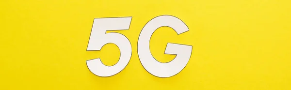 Top view of white 5g lettering on yellow background, panoramic shot — Stock Photo