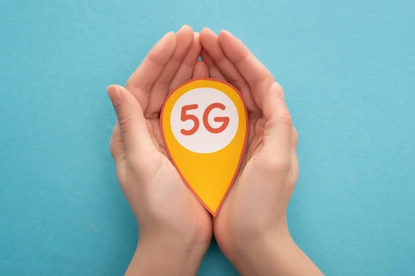 Vue recadrée de la marque de localisation de l'exploitation de la femme avec un lettrage de 5g sur fond bleu — Photo de stock