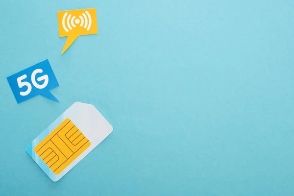 Top view of sim card and  speech bubbles with 5g lettering on blue background — Stock Photo