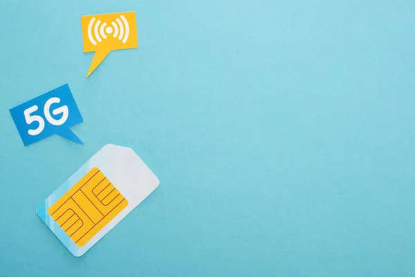 Top view of sim card and  speech bubbles with 5g lettering on blue background — Stock Photo