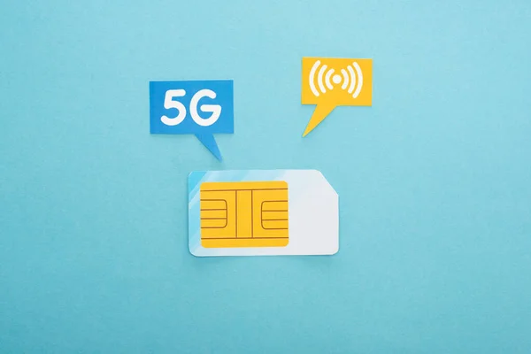 Vista superior do cartão SIM e bolhas de fala com letras de 5g no fundo azul — Fotografia de Stock