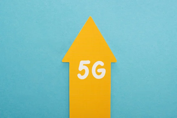 Top view of 5g yellow arrow on blue background — Stock Photo