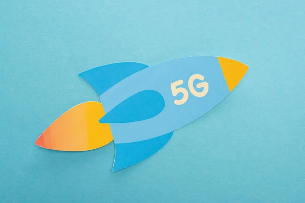 Vue du dessus de la fusée en papier avec lettrage 5g sur fond bleu — Photo de stock