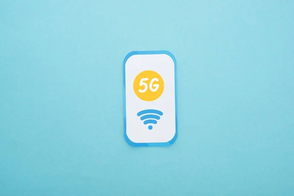 Top view of 5g lettering on paper smartphone on blue background — Stock Photo