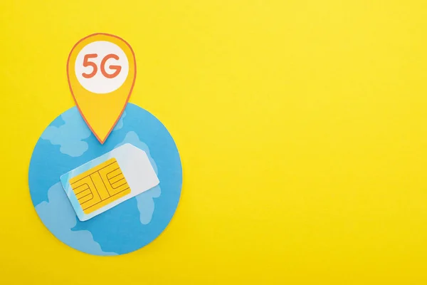 Vista superior do cartão SIM e letras 5g no globo no fundo amarelo — Fotografia de Stock