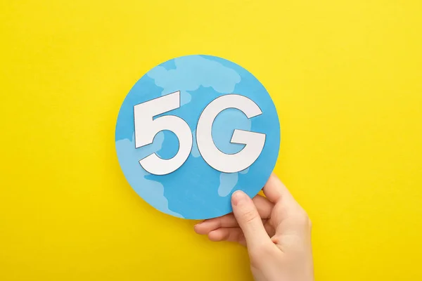 Cropped view of woman holding globe with 5g lettering on yellow background — Stock Photo