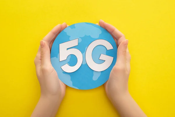 Vue recadrée de la femme tenant globe avec 5g lettrage sur fond jaune — Photo de stock