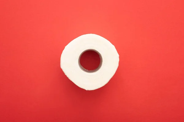 Vista superior del rollo de papel higiénico limpio blanco sobre fondo rojo - foto de stock