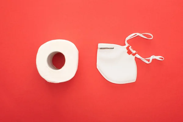 Top view of white clean toilet paper roll and safety mask on red background — Stock Photo