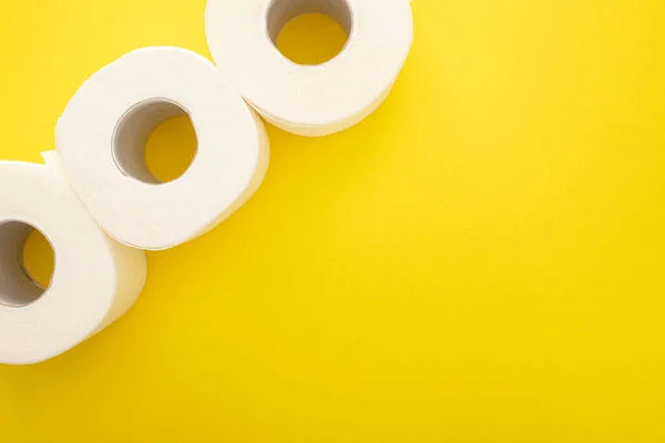 Draufsicht auf weiße Toilettenpapierrollen auf gelbem Hintergrund mit Kopierraum — Stockfoto