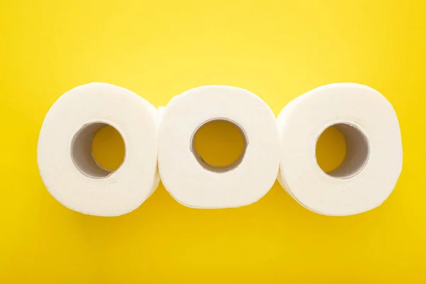 Pose plate avec rouleaux de papier toilette blanc sur fond jaune — Photo de stock