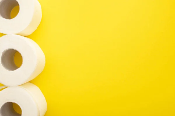 Top view of white toilet paper rolls on yellow background with copy space — Stock Photo