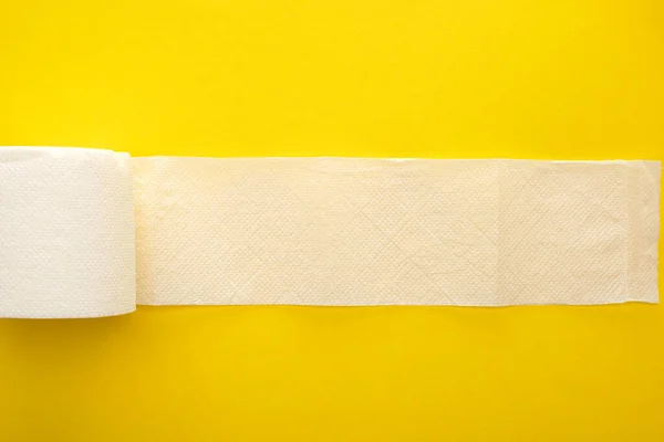 Vue du dessus du papier hygiénique blanc déroulé sur fond jaune — Photo de stock