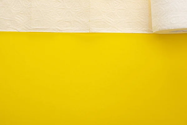 Vista superior del papel higiénico blanco desenrollado sobre fondo amarillo - foto de stock