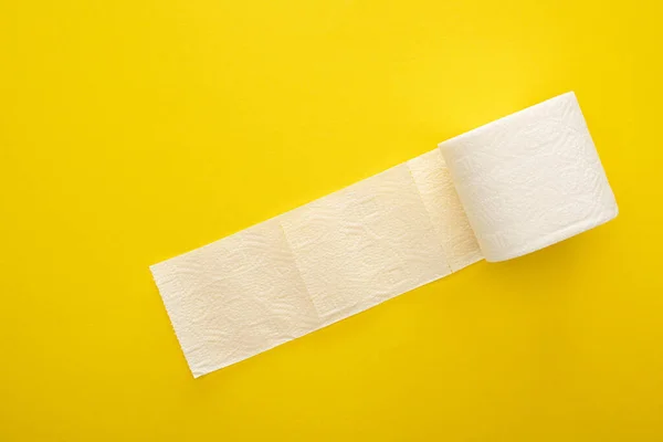 Vista superior del rollo de papel higiénico desenrollado sobre fondo amarillo - foto de stock