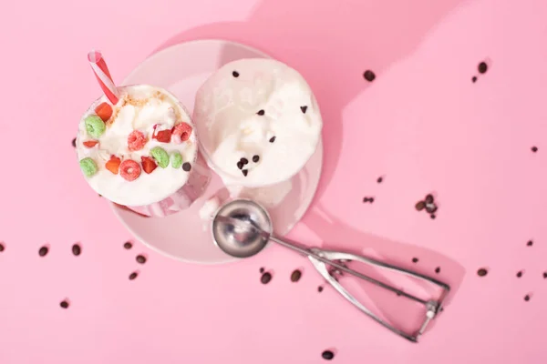 Top view of strawberry milkshakes and scoop on plate with coffee grains on pink — Stock Photo