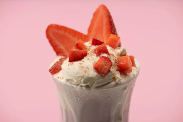 Selective focus of glass of milkshake with ice cream and cut strawberries isolated on pink — Stock Photo