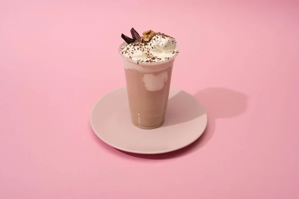 High angle view of disposable cup of chocolate milkshake on plate on pink background — Stock Photo