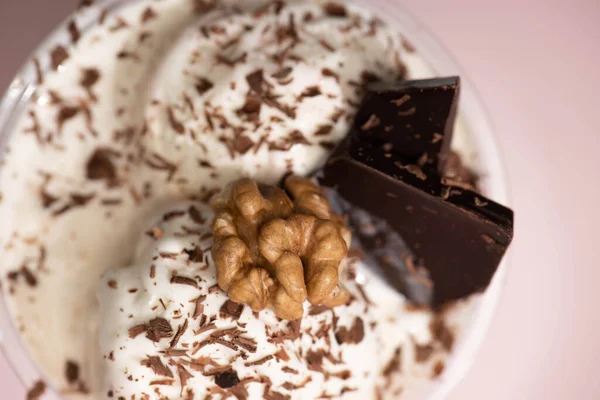 Vue du dessus de tasse jetable de milkshake avec crème glacée, noix, copeaux de chocolat et morceaux sur fond rose — Photo de stock