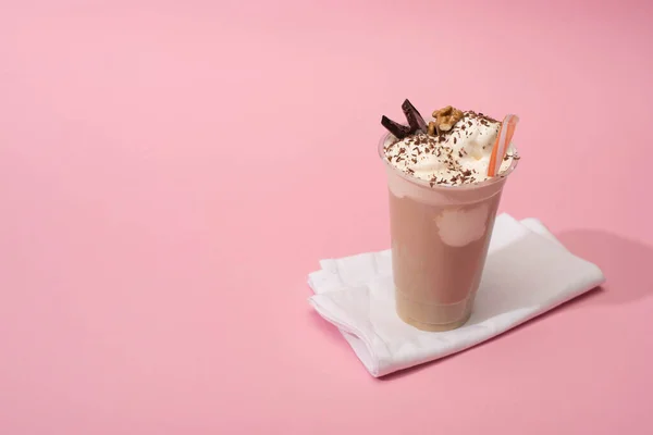 Vista de alto ângulo da xícara descartável de batido de chocolate com palha de bebida em guardanapos no fundo rosa — Fotografia de Stock